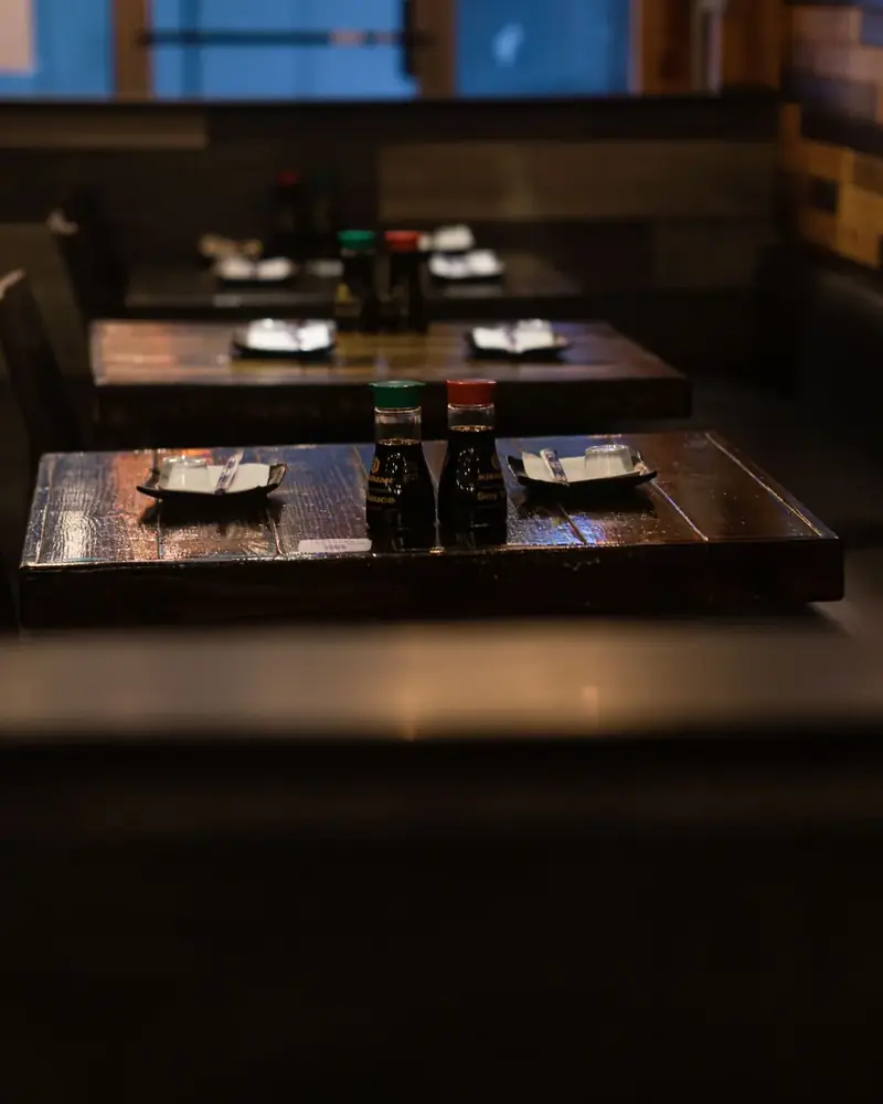 Empty restaurant tables set with soy sauce bottles and napkins, waiting for evening guests